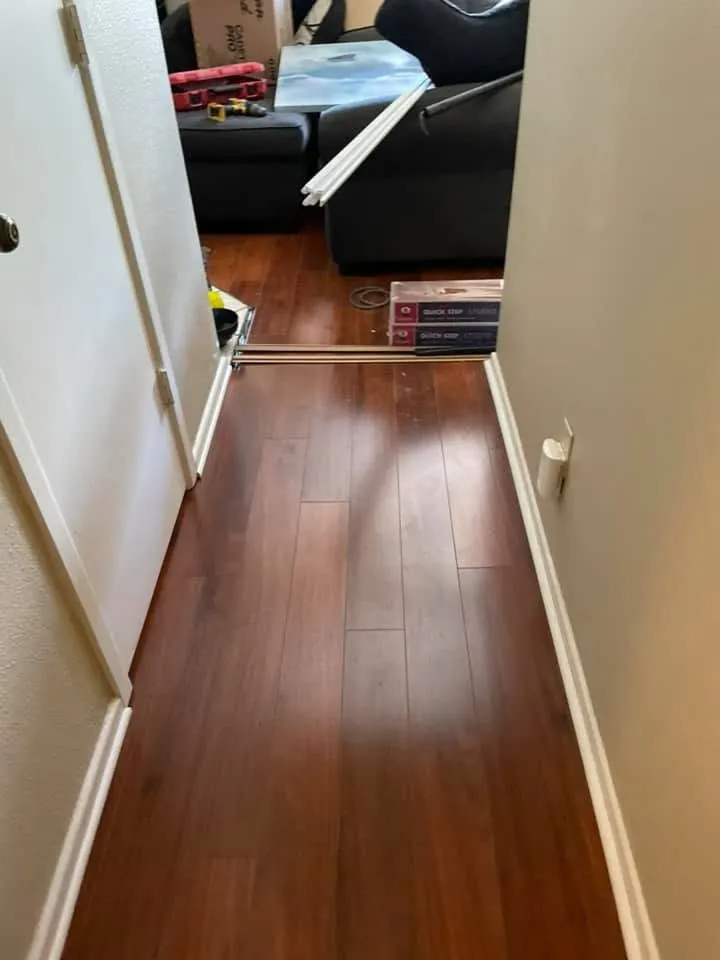 Dark wood look laminate floor running down a hallway into the living room
