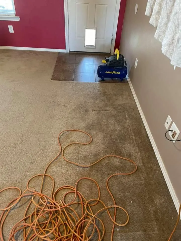 Bare subfloor prepared for new flooring in a room with a red accent wall